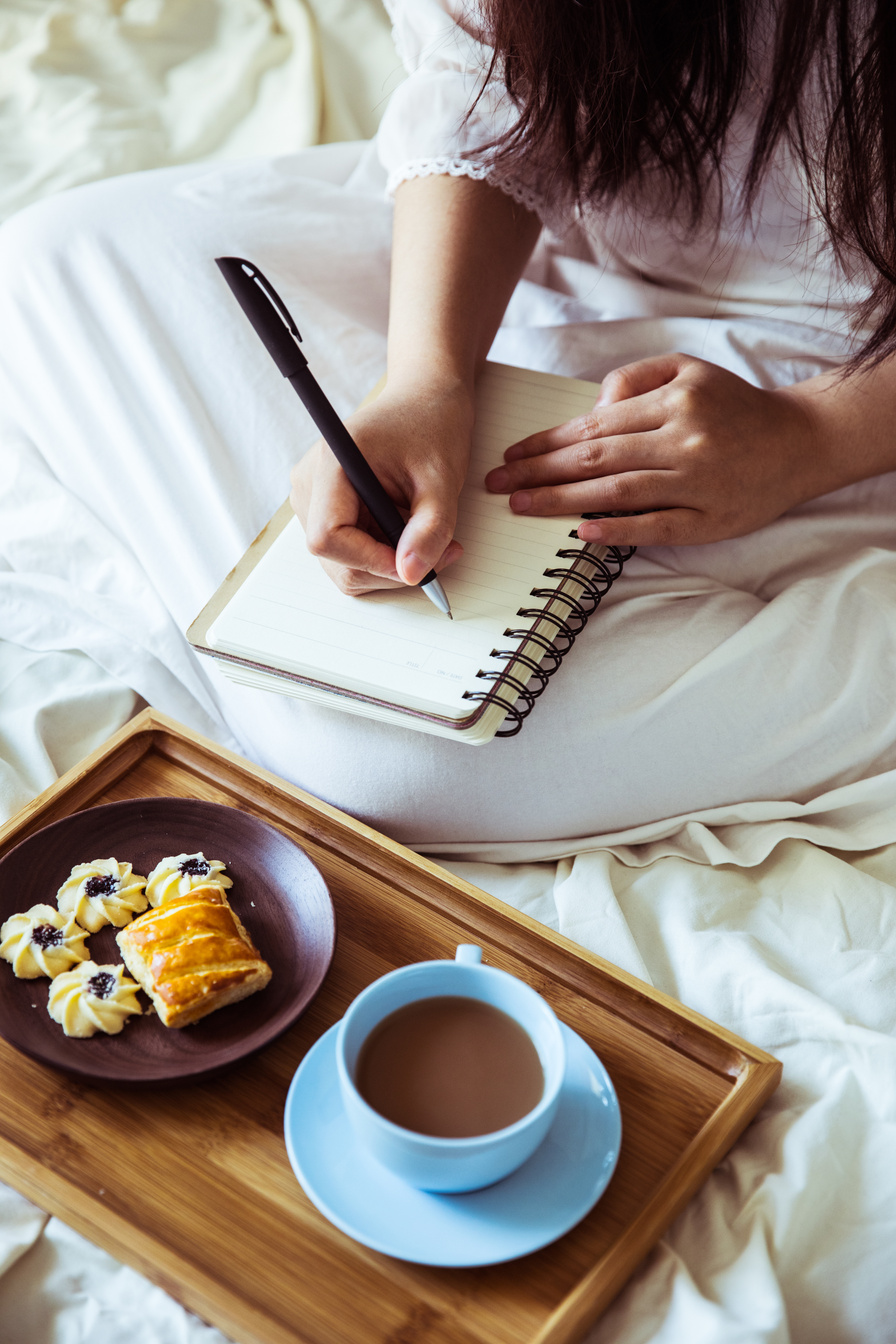 Woman writing diary in bed
